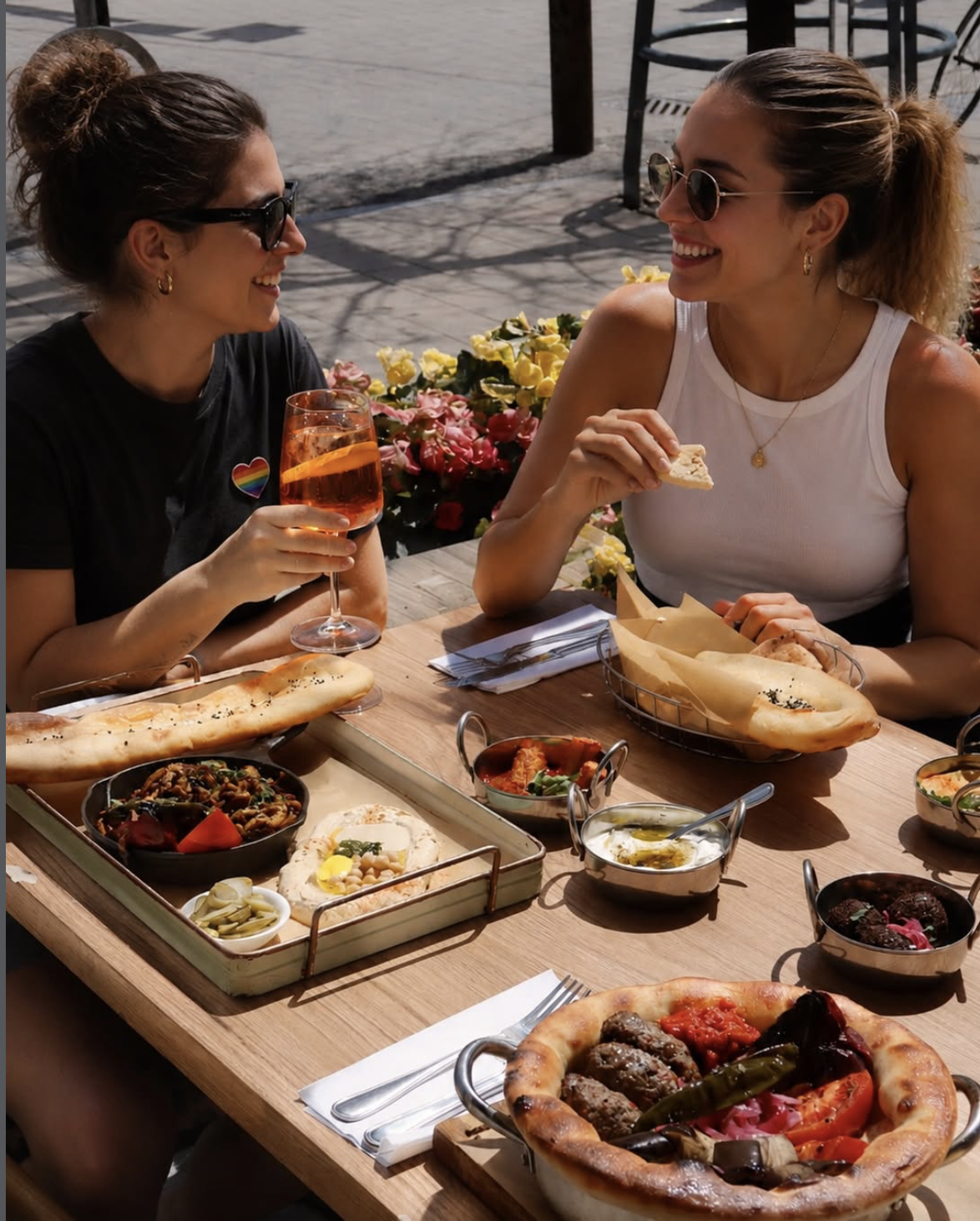 Friends sharing Mediterranean plates on the Cafe Landwer patio
