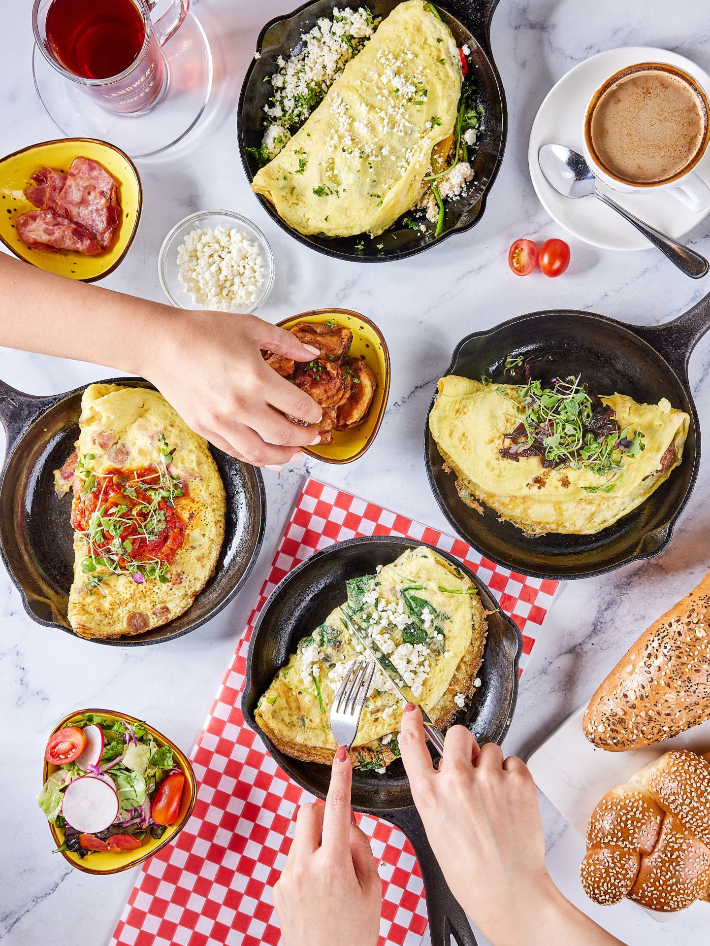 Skillet omelettes, coffee and fresh bread on a marble table