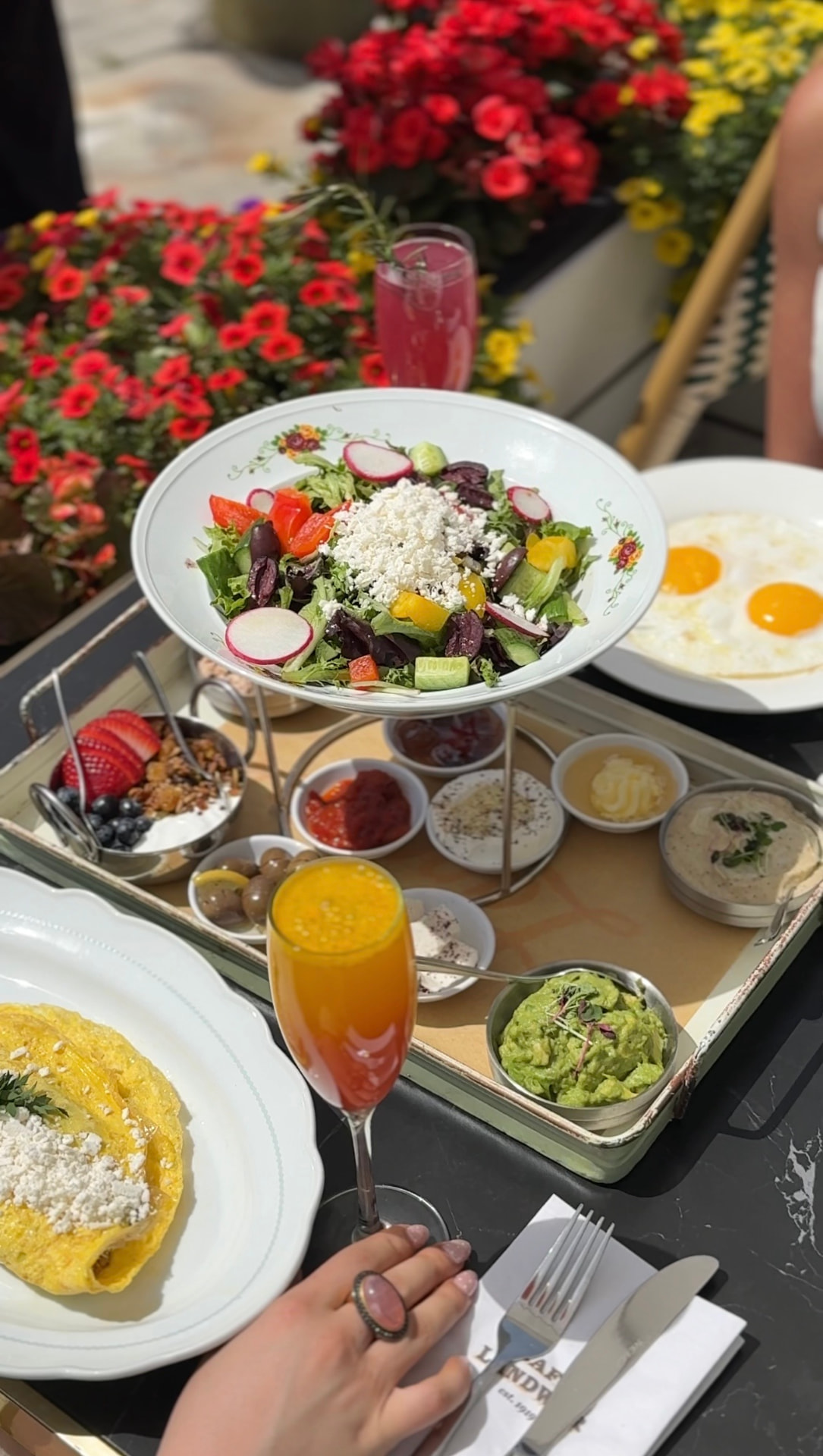Cafe Landwer brunch tray with mezze, salad, eggs and a mimosa